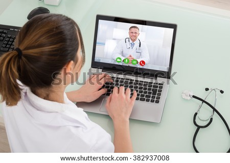 Young Female Doctor Video Chatting On Laptop In Clinic