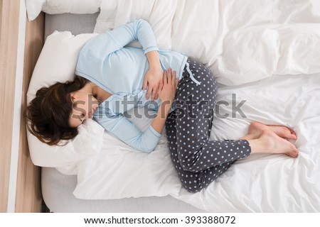 Young Woman With Stomach Ache Lying On Bed