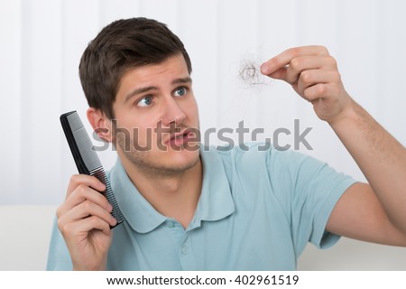 Young Man Holding Comb Looking At Loss Hair