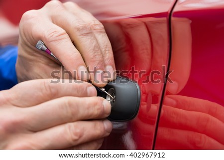 Close-up Of Person Hand Holding Lockpicker To Open Car Door