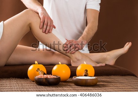 Close-up Of A Woman Getting Her Leg Waxed By Applying Wax Strips At Beauty Spa