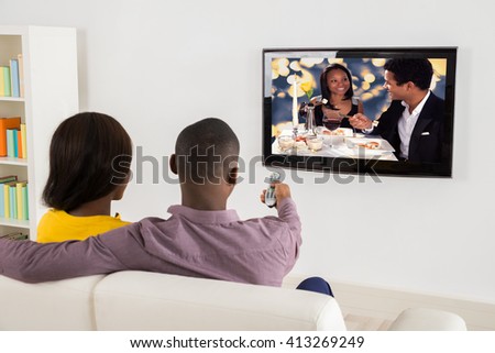 Happy African Couple Watching Television At Home