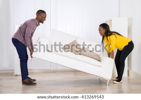 Young Happy African Couple Placing Sofa In Living Room