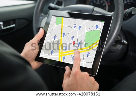 Close-up Of A Person Sitting In A Car Using GPS Service On Digital Tablet