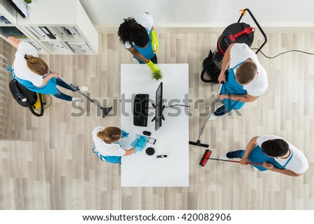 Group Of Janitors In Uniform Cleaning The Office With Cleaning Equipments