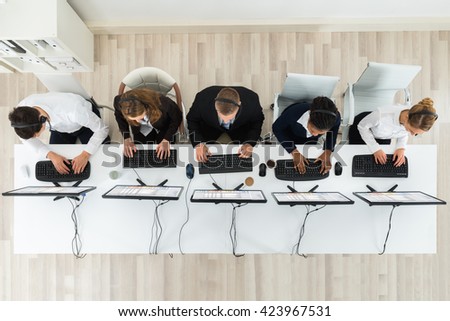 High Angle View Of Call Center Operators Working On Computers In Office