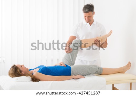Happy Mature Woman On Bed Receiving Leg Massage In Spa