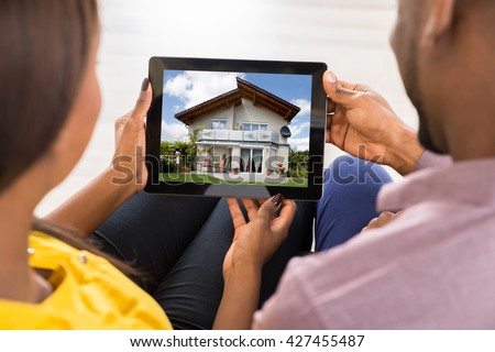 Close-up Of A Couple Looking At House On Digital Tablet