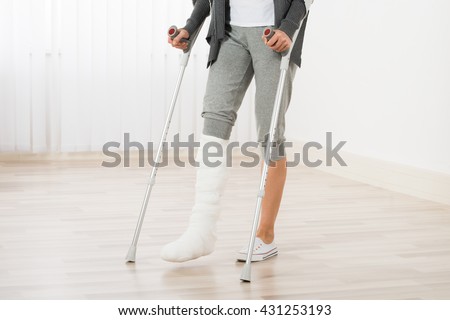 Close-up Of Woman Leg In Plaster Cast Using Crutches While Walking