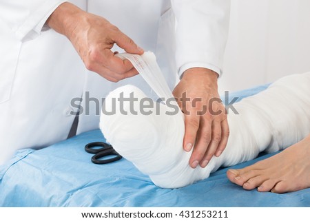 Close-up Of Doctor Hand Tying Bandage On The Leg Of Patient In Clinic