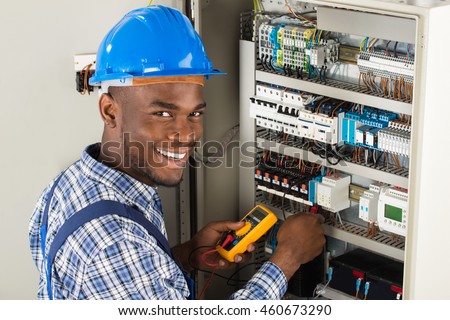 Young African Male Technician Examining Fusebox With Multimeter Probe