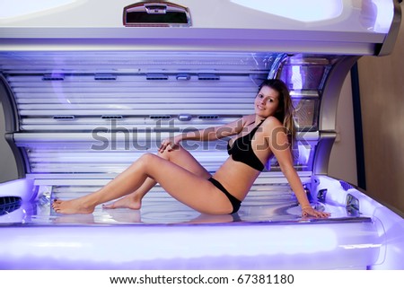 Young woman posing on tanning bed. Indoors solarium shot