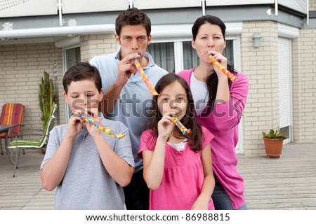Portrait of happy family blowing whistle and having fun in backyard