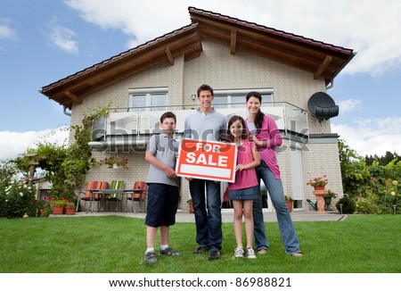 Portrait of young family selling their home holding for sale sign