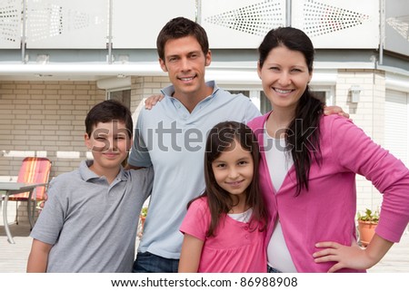Portrait of beautiful young family standing together outside their new house