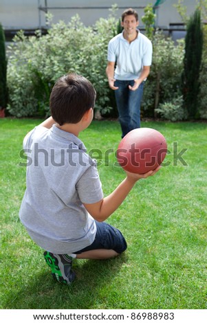 Little kid throwing football to his father in backyard