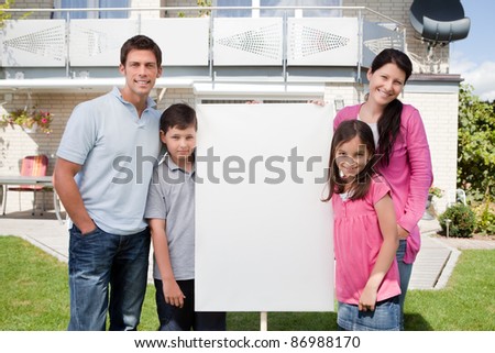 Portrait of small family standing outside with a empty sign board