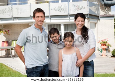 Portrait of caucasian family standing together in front of their new house