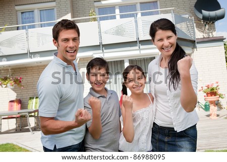 Portrait of excited family celebrating success in front of their home