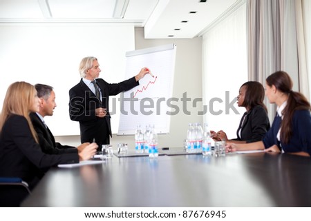 Senior male speaker giving presentation at a business meeting