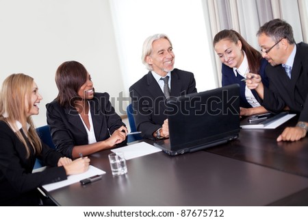 Happy mature business manager discussing targets on his laptop with his team