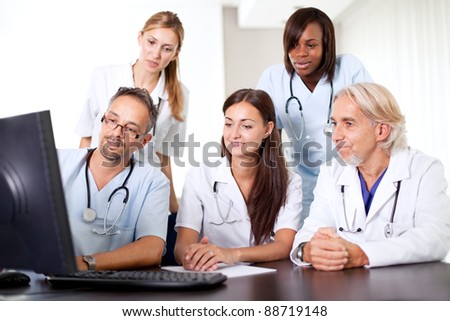 Friendly group of doctors at the hospital looking at a computer