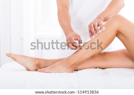 Close-up Of A Beautician Waxing Woman\'s Leg In Beauty Spa
