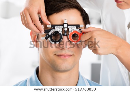 Close-up Of An Optometrist Checking Male Patient Vision With Trial Frame At Eye Clinic
