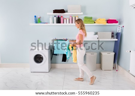 Happy Woman Washing Stained Clothes In Washing Machine In Utility Room