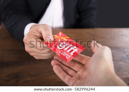 Close-up Of A Businessperson Hands Giving Gift Card To Other Businessperson