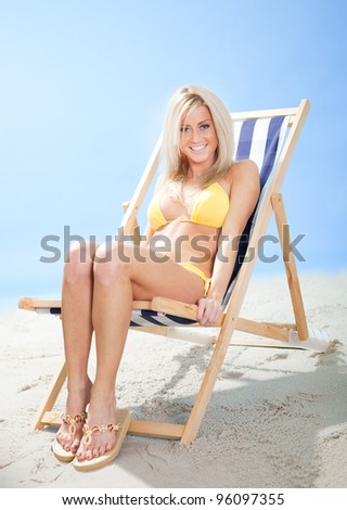 Beautiful young woman in bikini lying on a deckchair at the beach