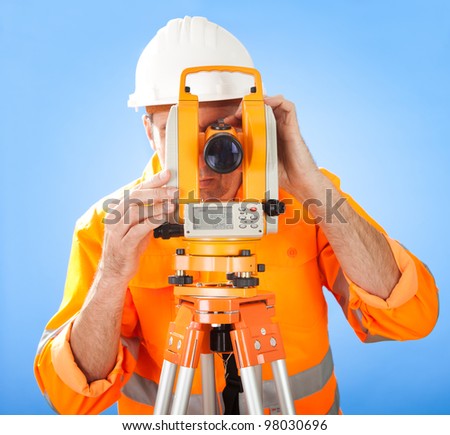 Portrait of Senior land surveyor working with theodolite at construction site