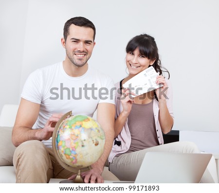 Young couple buying travel tickets online using laptop at home