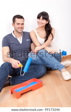 Young couple painting wall at home in blue