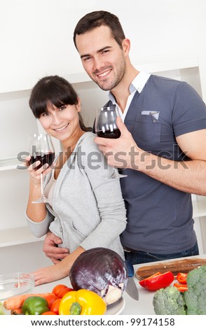 Lovely young couple cooking in the kitchen and drinking wine