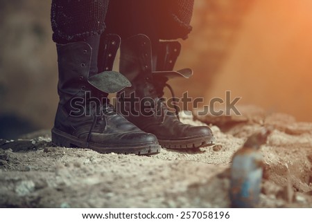 Workers dirty shoes. Army rough boots. Man standing in a field