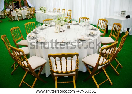 A view of a round banquet table with napkins and silverware set and a colorful flower centerpiece.