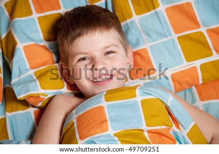 Cheerful boy in bed does not want to sleep