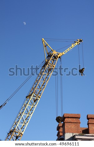 The yellow crane and red brick building under the moon in the blue sky vertical