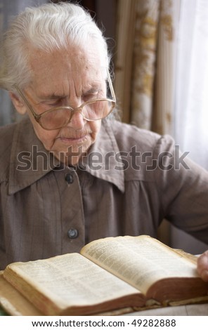 senior woman in glasses reading old Bible
