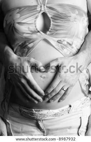 Father making heart shape on mother\'s belly without mother\'s hand