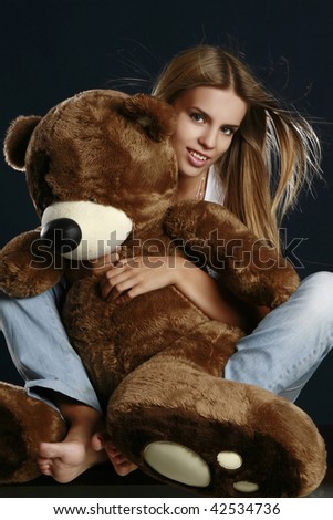 Young pretty woman with big teddy bear posing in studio.
