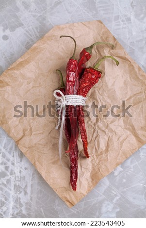 sheaf of dried red pepper and a piece of paper lying on a white table