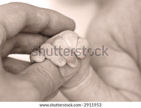 Baby\'s hand keeping adult finger - sepia