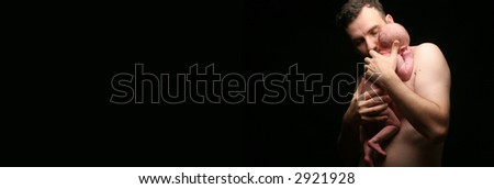Young father holing his newborn baby girl on a black background