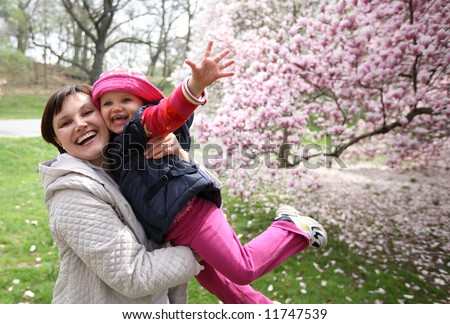 young mother and daughter play in a garden - spring
