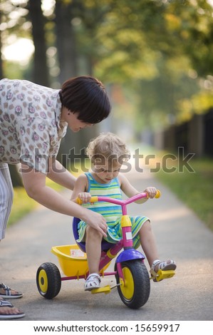 Mother teach her small daughter to drive bicycle