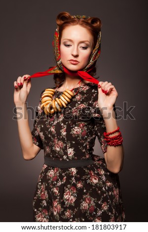 Girl in Russian style posing in red kerchief and bagels on the neck. Tying a red scarf.
