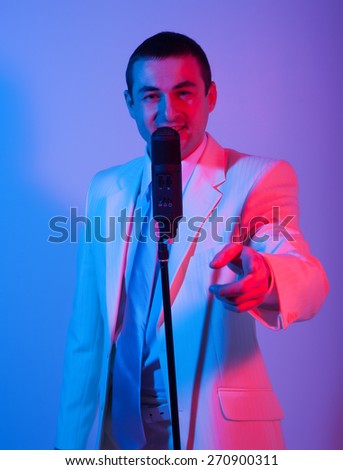 Man in white suit  with microphone. Vivid emotions. Colored background.