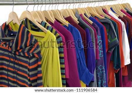 Row of casual clothes of different colors on wooden hangers